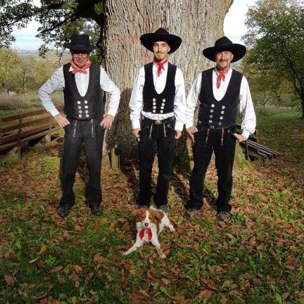Das Team der Zimmerei Posch in traditioneller Zimmermannstracht vor einem alten Baum